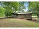 Cozy single story home with neutral siding and dark trim nestled among mature trees in a natural setting at 6658 Collins Ct, Riverdale, GA 30274