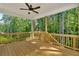 Large wooden back porch featuring a ceiling fan, wood railing, and a view of the trees at 1065 Low Water Crossing Nw, Acworth, GA 30101