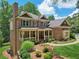 Elegant brick home with a covered front porch, mature trees, and meticulously landscaped front yard at 245 River Laurel Way, Woodstock, GA 30188