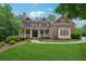Stunning brick home features a manicured lawn and inviting front porch with white columns at 245 River Laurel Way, Woodstock, GA 30188