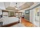 Luxurious bedroom featuring a tray ceiling, hardwood floors, and an adjacent bathroom at 245 River Laurel Way, Woodstock, GA 30188