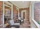 Charming covered porch with brick flooring, cozy seating, and classic white columns at 245 River Laurel Way, Woodstock, GA 30188