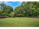 Expansive backyard with lush green lawn, mature trees, and a charming wooden fence at 4075 Hickory Fairway Dr, Woodstock, GA 30188