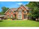 Beautiful two-story brick home with a lush green lawn, manicured landscaping and attractive curb appeal at 4075 Hickory Fairway Dr, Woodstock, GA 30188