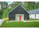 Charming exterior elevation of a modern home with black siding, a bright orange front door and a well manicured lawn at 587 Woods Nw Dr, Atlanta, GA 30318