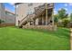 Large backyard featuring a well-maintained lawn, brick retaining wall, and an elevated deck with stairs at 2755 Evan Manor Ln, Cumming, GA 30041
