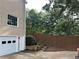 A view of the two-car garage with white doors and a brown fenced backyard beyond a lush bush at 3641 Bramblewood Way, Marietta, GA 30062