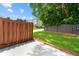A grassy backyard with a concrete patio area and wooden fence at 1343 Penhurst Dr, Lawrenceville, GA 30043