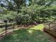Wooded backyard with mature trees, green grass, and a fenced garden area at 135 Woodcrest Dr, Covington, GA 30016