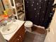 Bathroom features vanity with sink, toilet, shelves, and dark shower curtain with silver spiders at 135 Woodcrest Dr, Covington, GA 30016