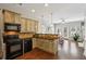 Open-concept kitchen with dark appliances, light-toned cabinets, and a bar overlooking the living area at 7275 Highland Blf # 8, Atlanta, GA 30328