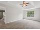 Bright main bedroom with a tray ceiling, ceiling fan, and large window overlooking trees at 1025 Pebble Creek Trl, Suwanee, GA 30024