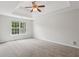 Large main bedroom with carpet, tray ceiling, ceiling fan, and a view of the backyard at 1025 Pebble Creek Trl, Suwanee, GA 30024