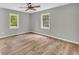 Bedroom with hardwood floors, ceiling fan, and windows offering natural light and exterior views at 3100 Meadow Trl, Loganville, GA 30052