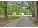 View down long paved driveway, leading to home with a detached garage and surrounded by mature trees and landscaped lawn at 3100 Meadow Trl, Loganville, GA 30052