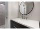 Sleek bathroom with black vanity, white countertop, a round mirror, and tiled shower at 1421 Peachtree Ne St # 401, Atlanta, GA 30309