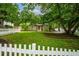Quaint home with a lush green lawn, mature trees, and a white picket fence at 1734 8Th St, Brookhaven, GA 30341