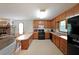 Open concept kitchen with wood cabinets, black appliances, and an extended counter space overlooking the living room at 3743 Wyntuck Nw Cir, Kennesaw, GA 30152