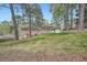 View of the brick house from the lush, sloping backyard with mature trees at 4089 Menlo Dr, Tucker, GA 30084
