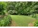 Backyard featuring a well-manicured lawn, surrounded by lush trees and shrubbery at 4987 Day Lily Nw Way, Acworth, GA 30102