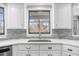 Bright kitchen with stainless sink, stylish backsplash, white cabinets, and a view from the window at 6313 Shoreland Cir, Buford, GA 30518