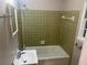 Bathroom featuring a bathtub with green tiling surround and a sink with mirror at 4902 Pine Hill E Ct, Stone Mountain, GA 30088