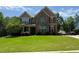 Charming two-story home boasts a stone and siding facade, complemented by a lush green lawn and well-manicured landscaping at 8340 Nolandwood Ln, Villa Rica, GA 30180