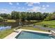 Aerial view of private pool and deck overlooking lush landscaping and lake at 1408 Chloe Dr, Lawrenceville, GA 30043