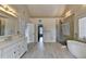 Bright bathroom with a soaking tub, walk-in shower, double vanity and wood-look tile floor at 189 Azalea Chase Dr, Suwanee, GA 30024