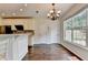 Bright kitchen with dark hardwood floors, white cabinetry, granite counters, and a charming chandelier at 189 Azalea Chase Dr, Suwanee, GA 30024