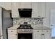 Close-up of kitchen featuring white cabinetry, mosaic backsplash, granite counters, and stainless appliances at 189 Azalea Chase Dr, Suwanee, GA 30024