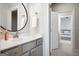 Modern bathroom featuring a round mirror, white countertops, and gray cabinets, with view of the bedroom beyond at 247 Widener Way, Peachtree City, GA 30269