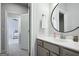 Modern bathroom featuring a round mirror, white countertops, and gray cabinets, with view of the bedroom beyond at 247 Widener Way, Peachtree City, GA 30269