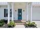 Inviting front porch with a blue door, decorative plants, classic columns, and elegant outdoor lighting at 247 Widener Way, Peachtree City, GA 30269