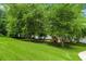 Spacious backyard with lush green lawn and mature trees leading down to a lake, with a charming playset at 5755 Riley Rd, Cumming, GA 30028