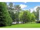Beautiful backyard with lush green grass, mature trees, and a glimpse of the lake at 5755 Riley Rd, Cumming, GA 30028