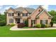 Traditional brick home featuring a well-manicured lawn, mature landscaping, and a welcoming entrance at 5755 Riley Rd, Cumming, GA 30028