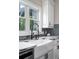 Close up of a sink with a window, black faucet, white cabinets, and stone countertop at 5755 Riley Rd, Cumming, GA 30028