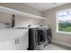 Bright laundry room with a large basin sink, white cabinets, stone counters, and modern washer and dryer at 5755 Riley Rd, Cumming, GA 30028