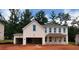 Two-story white brick home with unfinished landscaping, covered porch, and a partially finished garage at 6955 Melody Ridge Rd, Buford, GA 30518