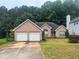 Charming brick home featuring a two-car garage and a well-maintained front lawn and lush green trees at 7513 Sugarcreek Dr, Riverdale, GA 30296