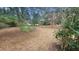 Wide shot of a flat, open backyard, partially covered in leaves, and surrounded by mature trees and shrubs at 3873 Jane Marie Ln, Decatur, GA 30035