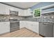 Beautiful kitchen with white cabinetry, stainless appliances, mosaic backsplash, and wood-look floors at 4753 Klondike Cv, Lithonia, GA 30038