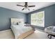 This bedroom has a ceiling fan, light-colored walls, large window, and a comfy chair at 5418 Amity Dr, Powder Springs, GA 30127
