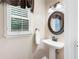 Powder room with pedestal sink, decorative oval mirror, updated fixtures, and window at 5418 Amity Dr, Powder Springs, GA 30127