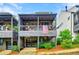 Multi-level townhouse with covered porch featuring wood railing; front yard landscaped with trees and bushes at 10862 Serenbe Ln, Chattahoochee Hills, GA 30268