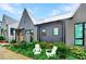 Charming home featuring a metal roof, gray vertical siding, an orange door and inviting front lawn with two white chairs at 10862 Serenbe Ln, Chattahoochee Hills, GA 30268