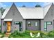 Charming home featuring a metal roof, gray vertical siding, an orange door and inviting front lawn with two white chairs at 10862 Serenbe Ln, Chattahoochee Hills, GA 30268