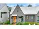 Home exterior features a grey facade with an orange front door, metal roof, and lush landscaping at 10862 Serenbe Ln, Chattahoochee Hills, GA 30268