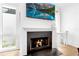 Cozy living room featuring a fireplace, large TV, hardwood floors, white walls, and a small table near the window at 10862 Serenbe Ln, Chattahoochee Hills, GA 30268